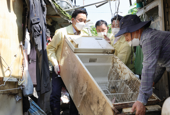 조성명(맨 왼쪽) 서울 강남구청장이 지난 12일 수해를 입은 강남구 개포동 구룡마을에서 못 쓰게 된 냉장고를 집 밖으로 옮기고 있다. 강남구 제공